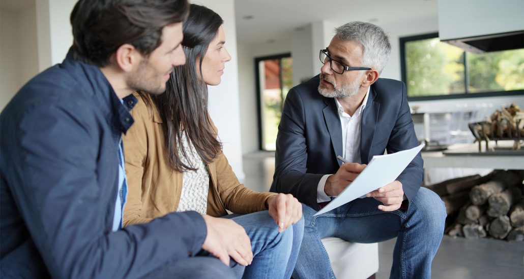 Couple with real-estate agent looking at contract in modern house